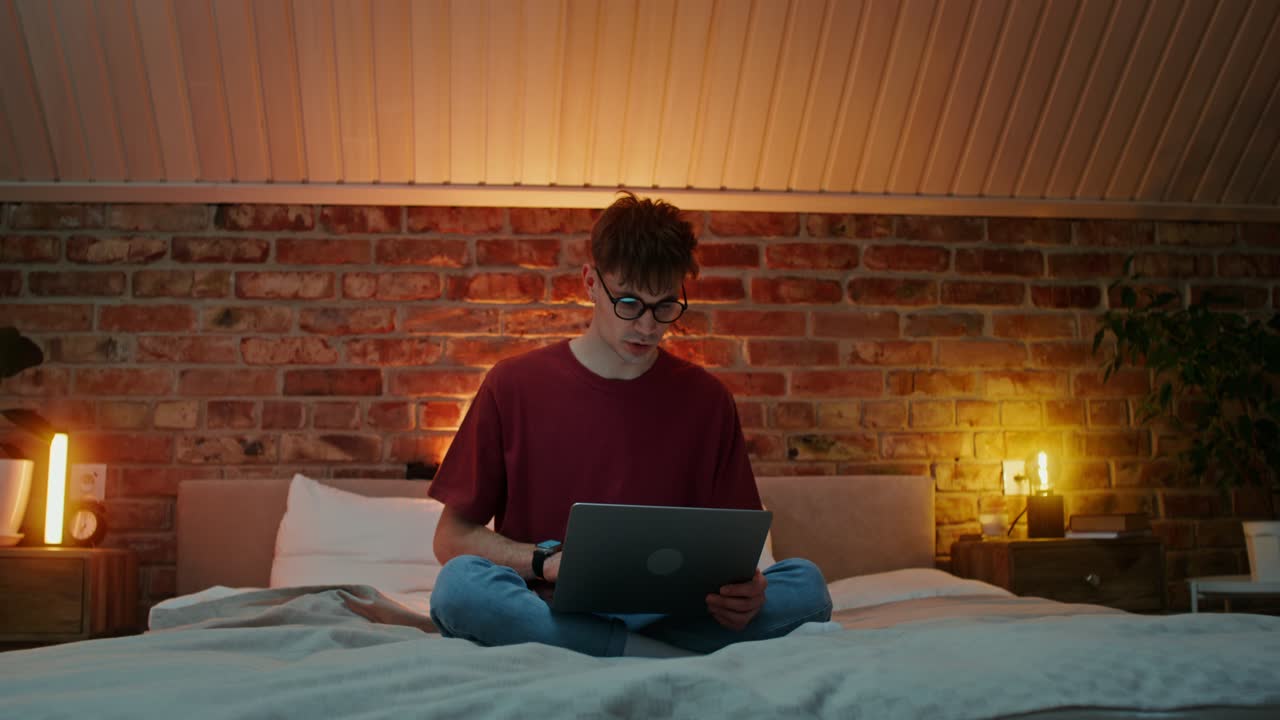 Man Working on Laptop in Bed at Night