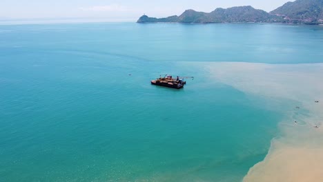 aerial drone of ocean oil, gas offshore platform rig in the shallows of capital dili, timor leste in southeast asia, popular tourist destination of cristo rei statue in the distance