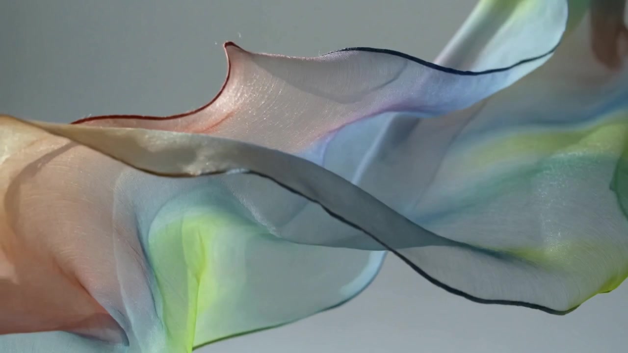 Billowing sheer ribbon shifting across neutral backdrop under soft side light, driven by breeze