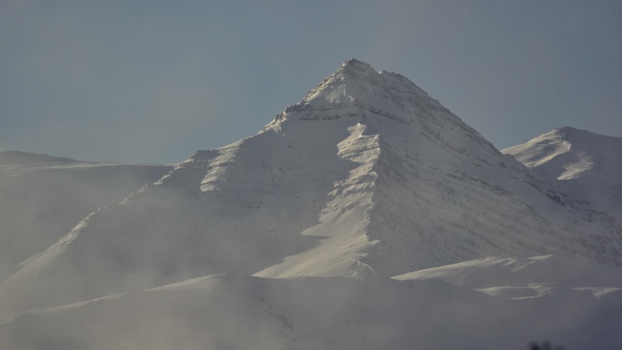Snow-covered mountain peak with mist at the base
