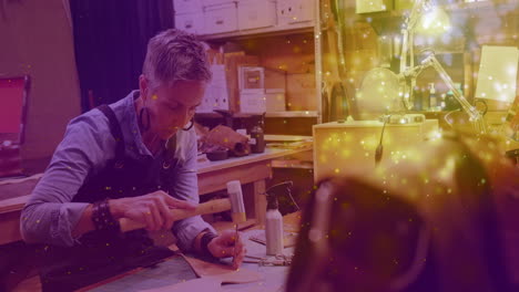 animation of glowing light over caucasian woman working in workshop