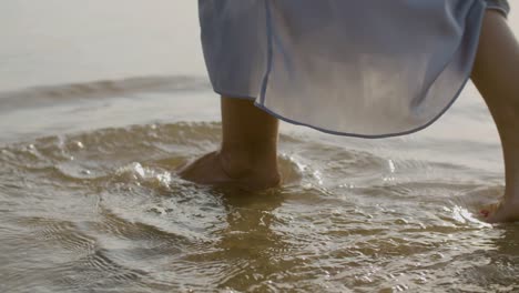 legs closeup of woman with red nails walking in sea water.