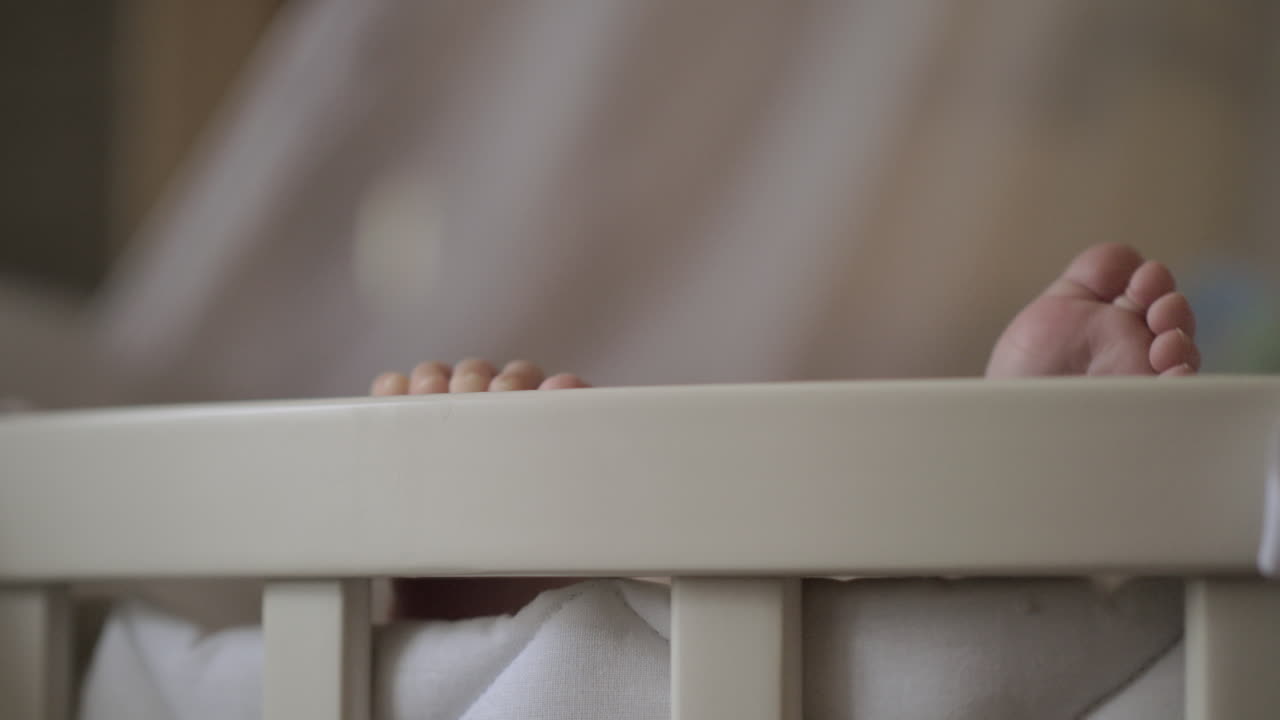 Piedini di neonato fuori dalla culla