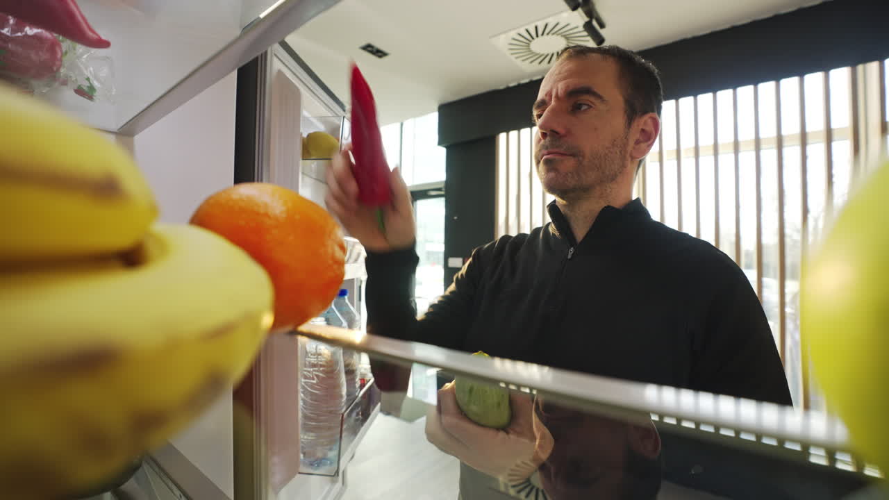 Man looking into a refrigerator filled with fruit