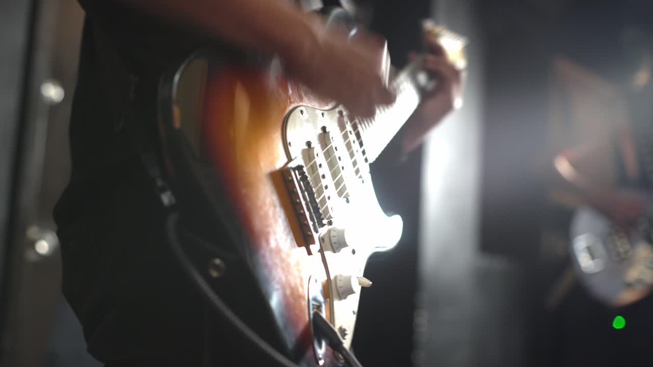 Konserde elektro gitar çalan genç bir kişi, yakın çekim.