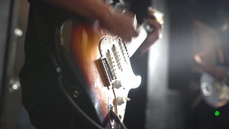 young person play with electric guitar at concert, close up view
