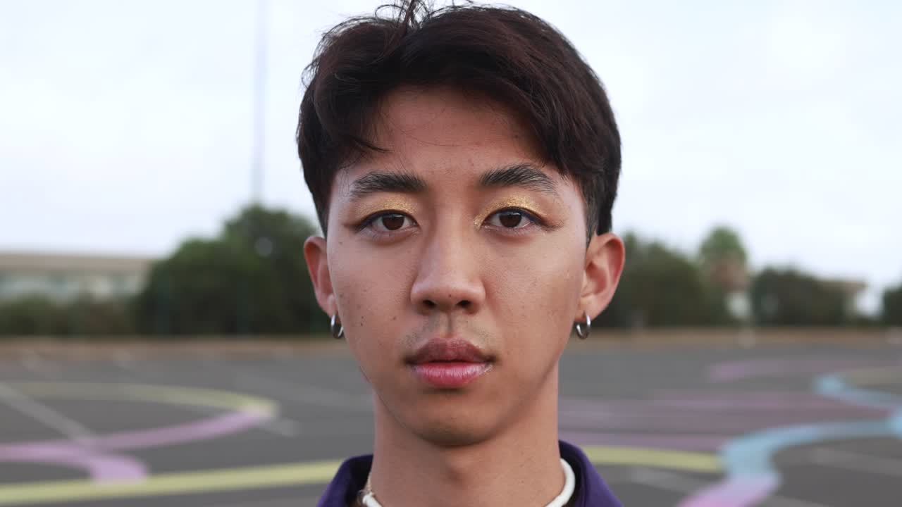 Gay chinese man with make-up looking on camera outdoor