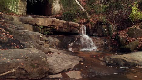 rocky creek falls leading to dark, overgrown tunnel