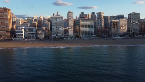 The-sandy-beach-at-Benidorm,-Spain---pull-back-aerial-reveal