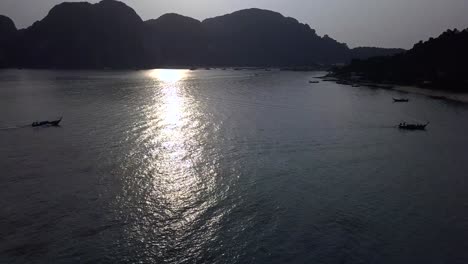 4K-AERIAL-FORWARD-VIEW-of-SUNSET-behind-incredible-rock-mountains-and-water-bay-in-Thailand,-Phi-Phi-Don-Island,-surrounding-mountains