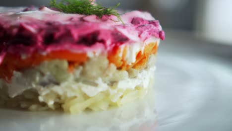 traditional russian salad with beetroot and herring vegetables, lying on a wooden table in a white plate