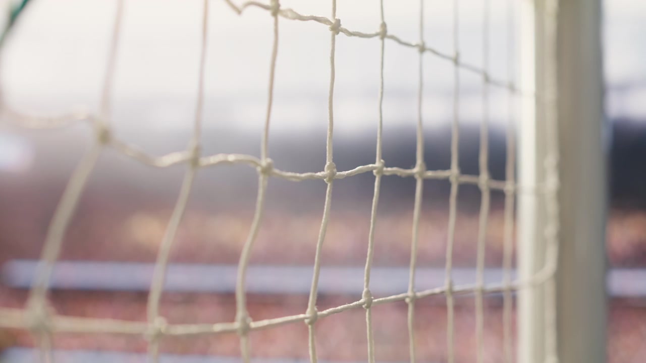 Selective focus goal net and post detail on football pitch under stadium light