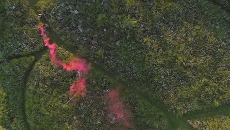 tomada de un dron de dos amigas corriendo por el campo con una llamarada de humo