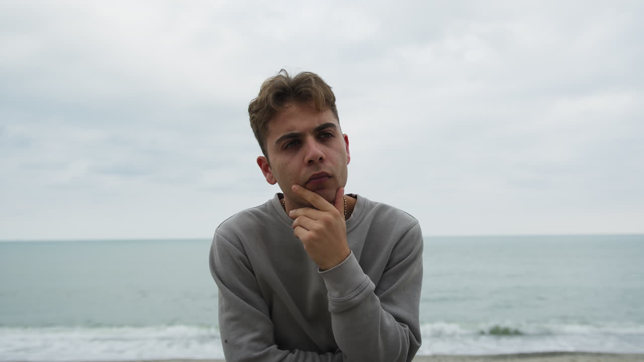 Pensive Boy Near The Ocean On A Cloudy Day