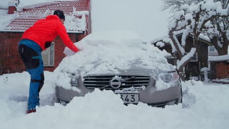 Man-use-snow-brush-to-remove-snow-from-car-after-heavy-snowfall