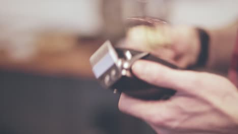 Hairdresser-tools.-Close-up-of-male-hands-brushing-electric-hair-clippers