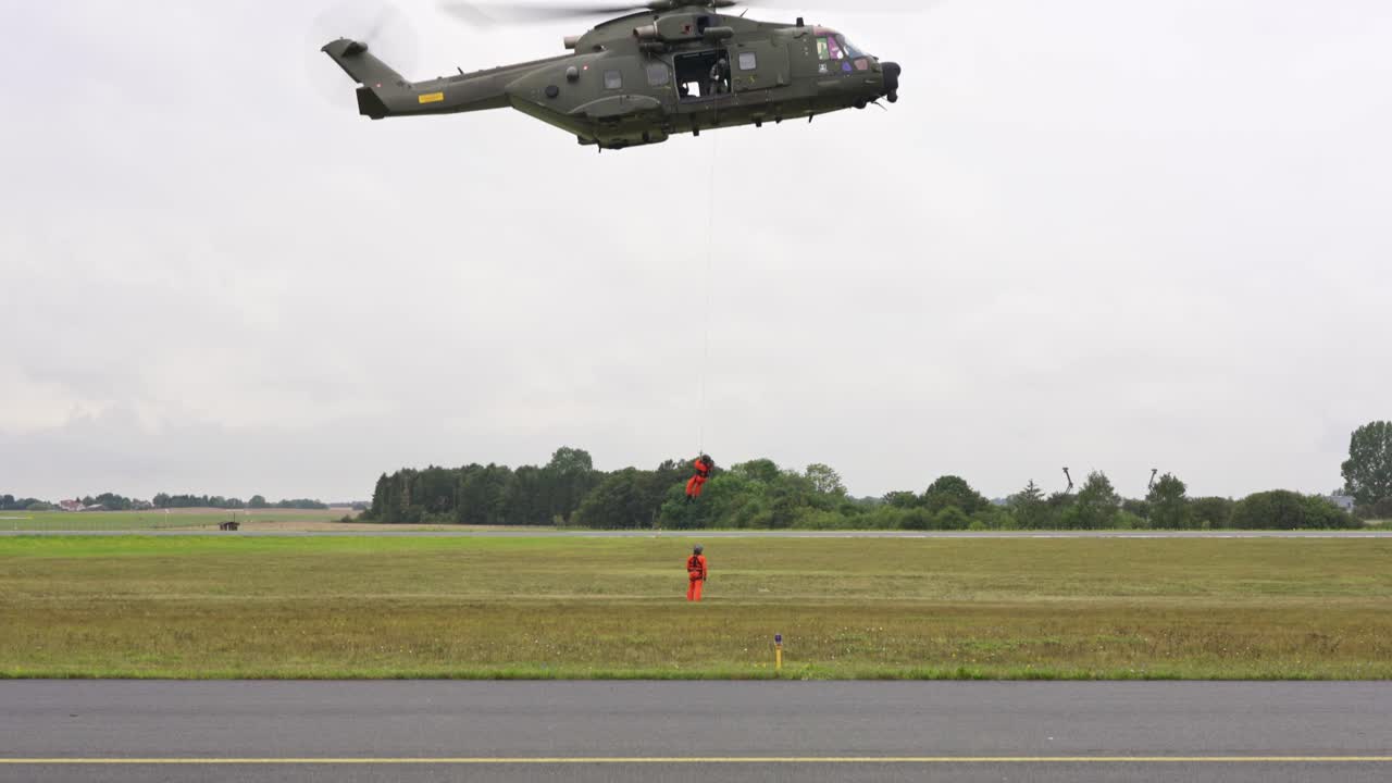 Rescue helicopter crew rescuing ground  crew via wire lifting