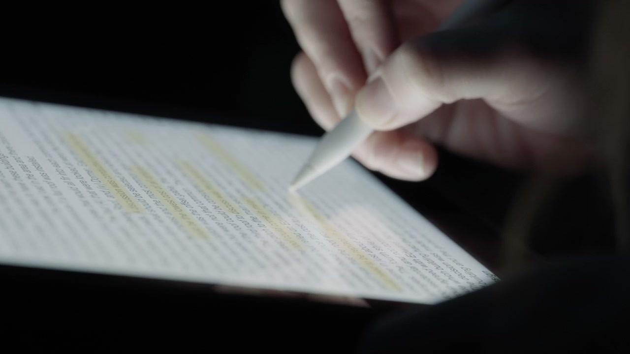 Pessoa lendo um texto e destacando-o com uma caneta em um tablet
