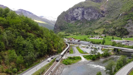 aerial: train by a river entering to flåm in norway