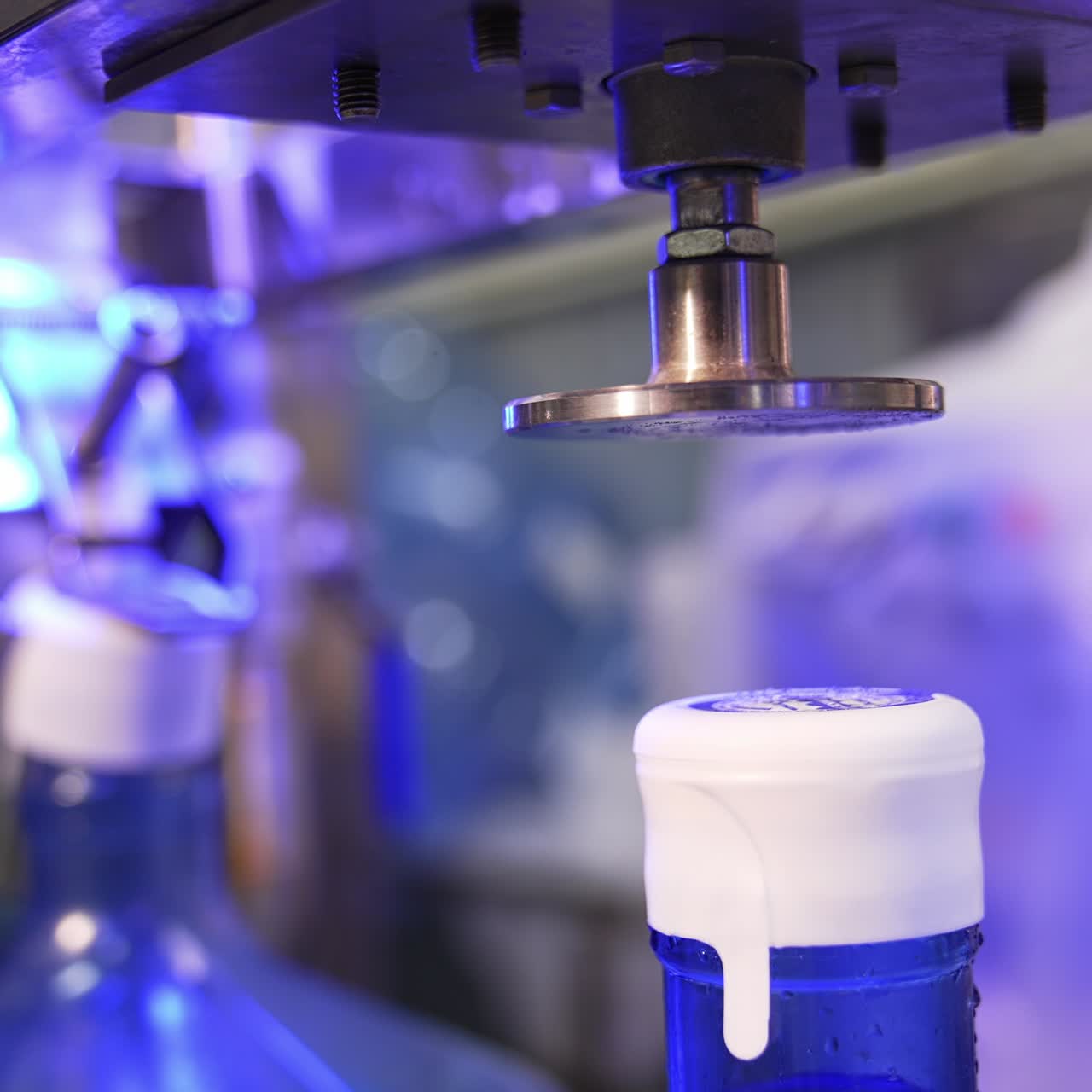 Automatic machine putting and stamping the cork at the flask. Bottles are filled with water at backdrop in blur
