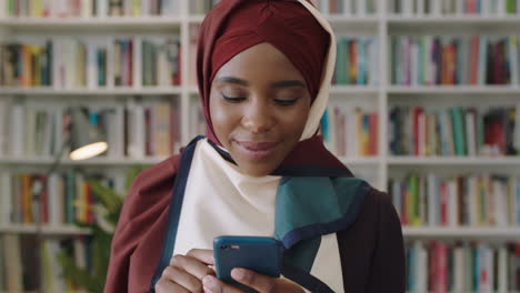 Retrato-De-Una-Joven-Y-Encantadora-Mujer-Afroamericana-Riéndose-Mirando-A-La-Cámara-Estudiante-Parada-En-La-Biblioteca