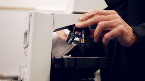 a college professor cleaning the lens of a microscope to show his students in a biology research laboratory slide left