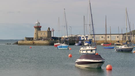 Leuchtturm-Von-Howth-Mit-Yachten-Und-Hochseebooten,-Die-Vor-Der-Küste-Im-Hafen-Verankert-Sind