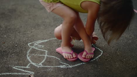 a little girl drawing a circle around her feet with chalk