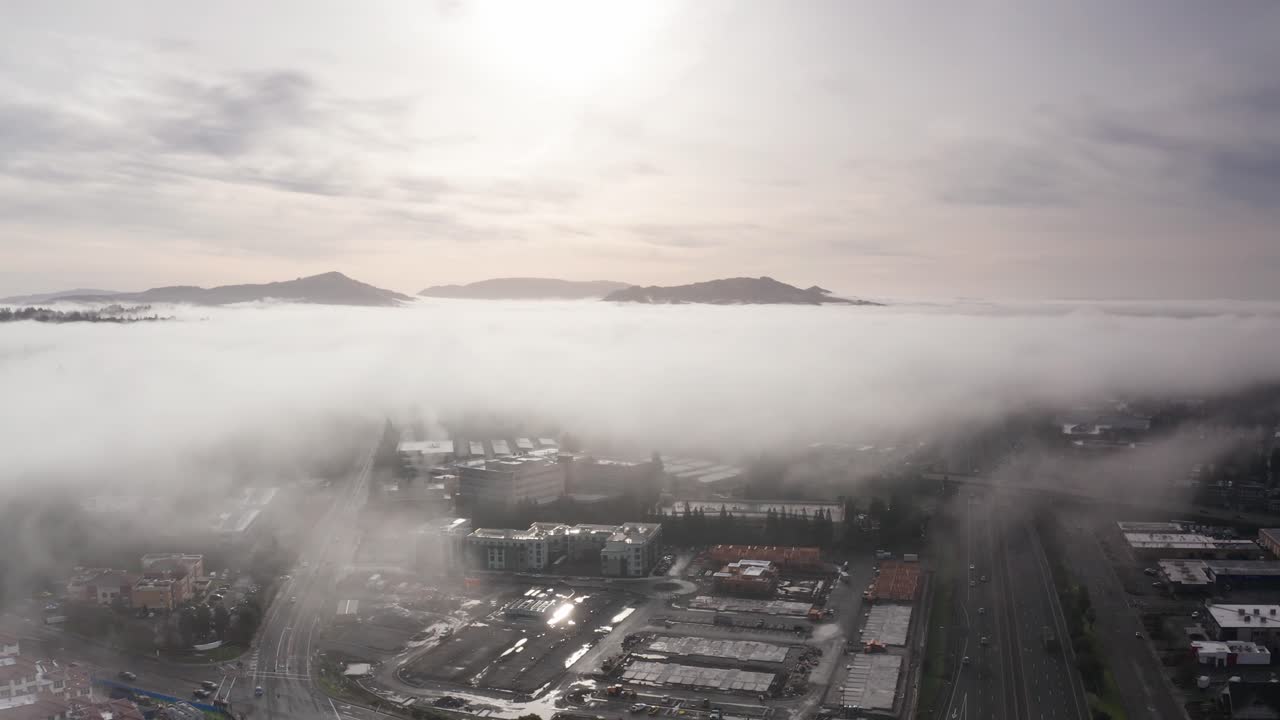 Wide panning aerial dolly shot of hills rising above fog along Highway 101 in Santa Rosa, California. 4K