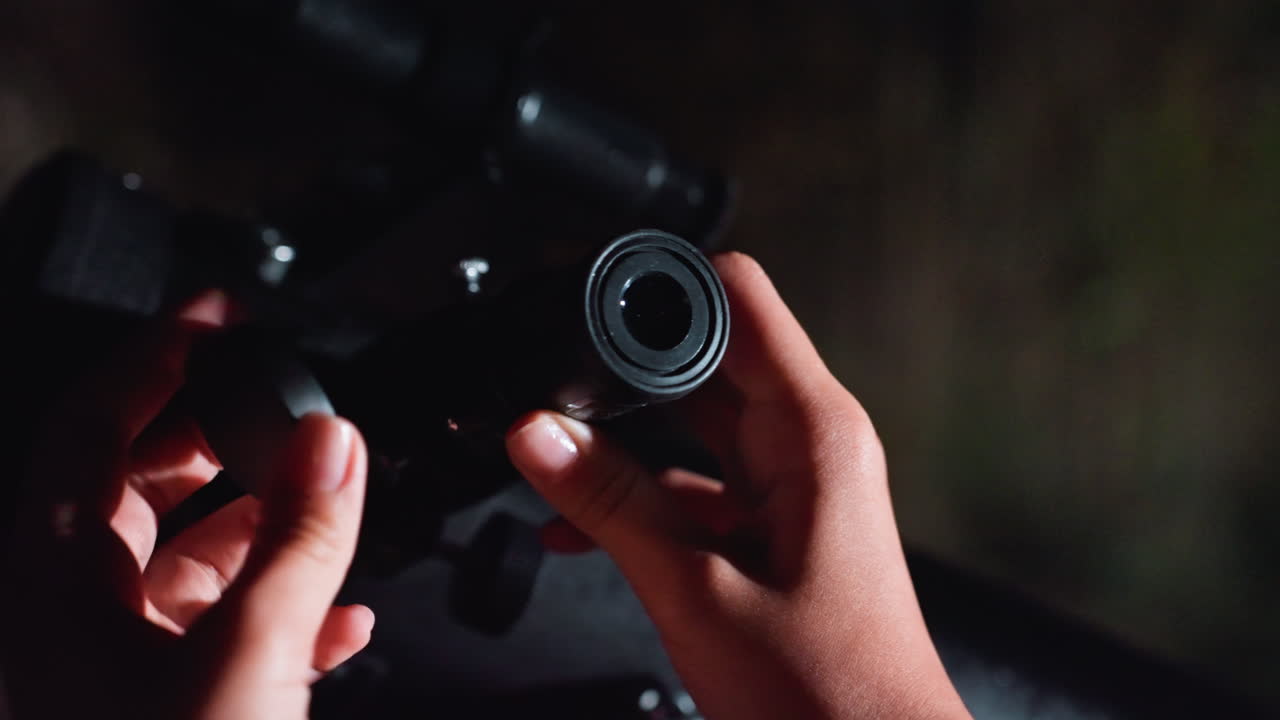 Hænder justerer teleskopets okular under nattehimlen, filmisk nærbillede af fingre, der monterer okularet på teleskopet, blød bokeh-baggrund, stativ og justeringsknap synlig, rolig baghave-atmosfære