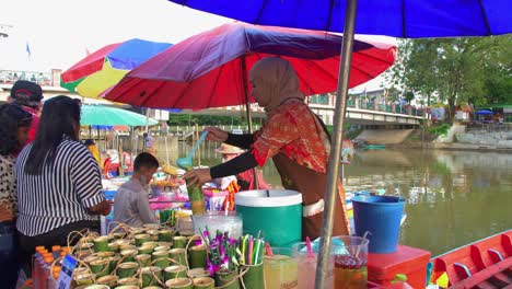Muslimische-Junge-Frau,-Die-Säfte-In-Kartons-Auf-Einem-Schwimmenden-Markt-In-Thailand-Verkauft