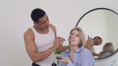 apuesto hombre negro aplicando exfoliante a una mujer