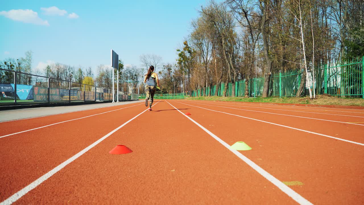 Young woman go in for sport run at the stadium track in the morning. Summer outdoors training