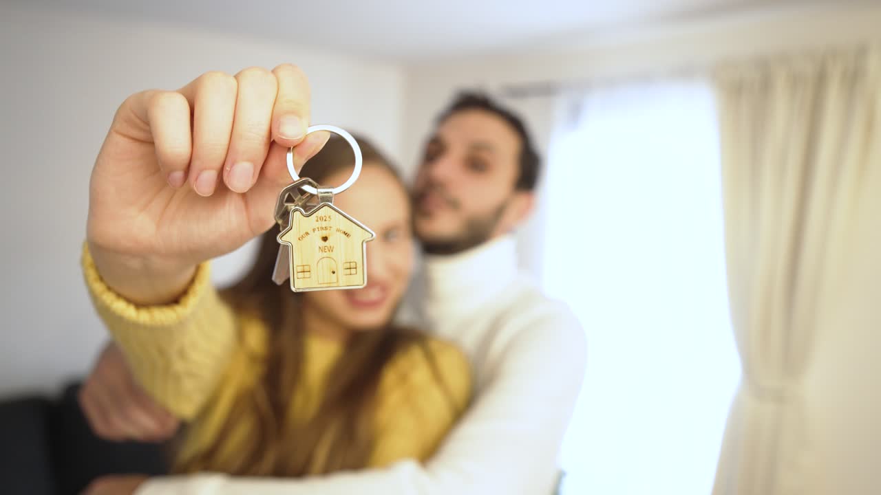 Una coppia felice festeggia la sua nuova casa. La donna tiene orgogliosamente la chiave a fuoco, simbolo di entusiasmo, successo e l'inizio di un bellissimo capitolo insieme