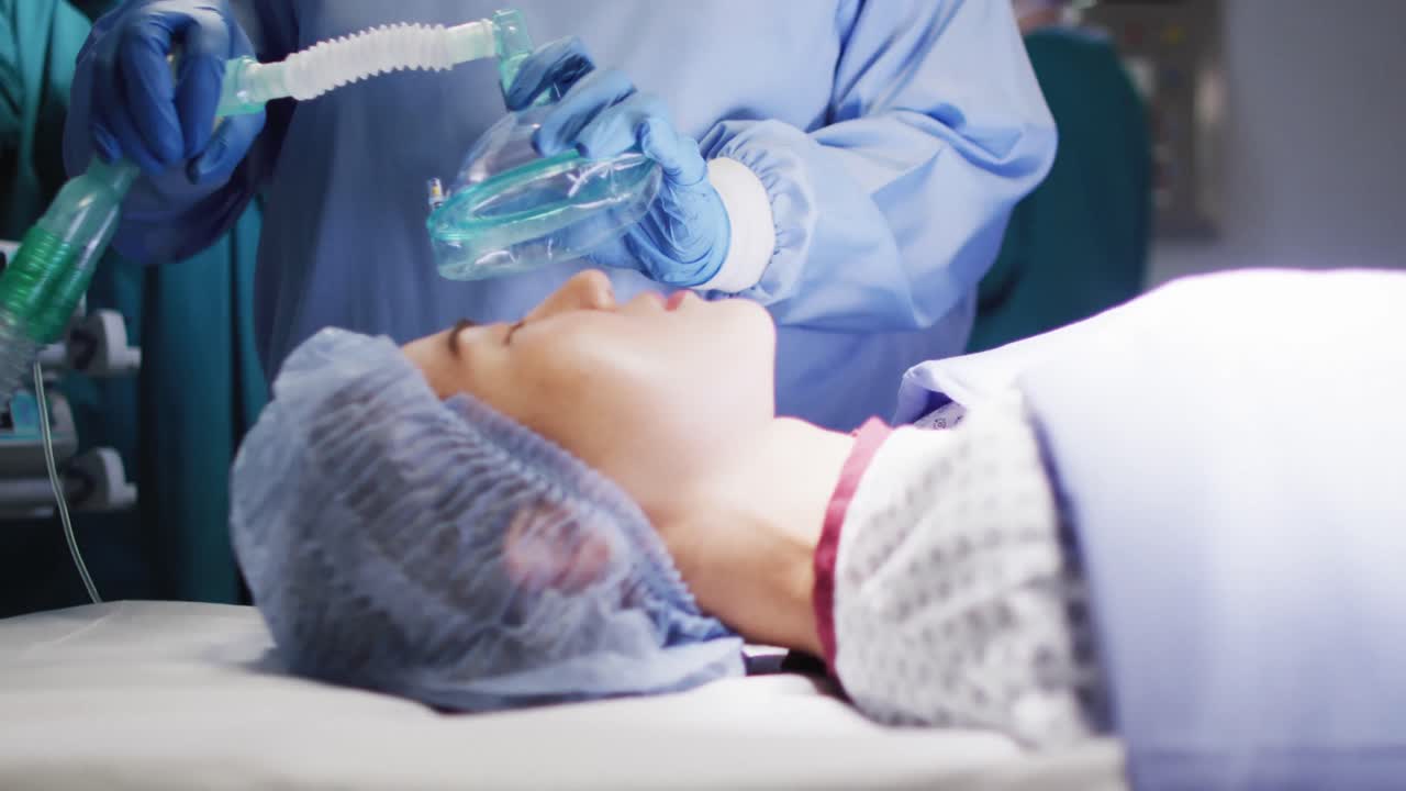 수술실 에서 아시아 여성 환자 에게 가스 를 주는 수술 조수 의 중간 부분 의 영상