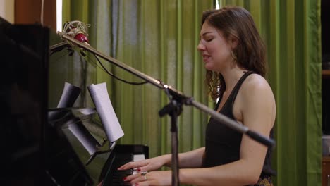 woman singing and playing piano in a music studio