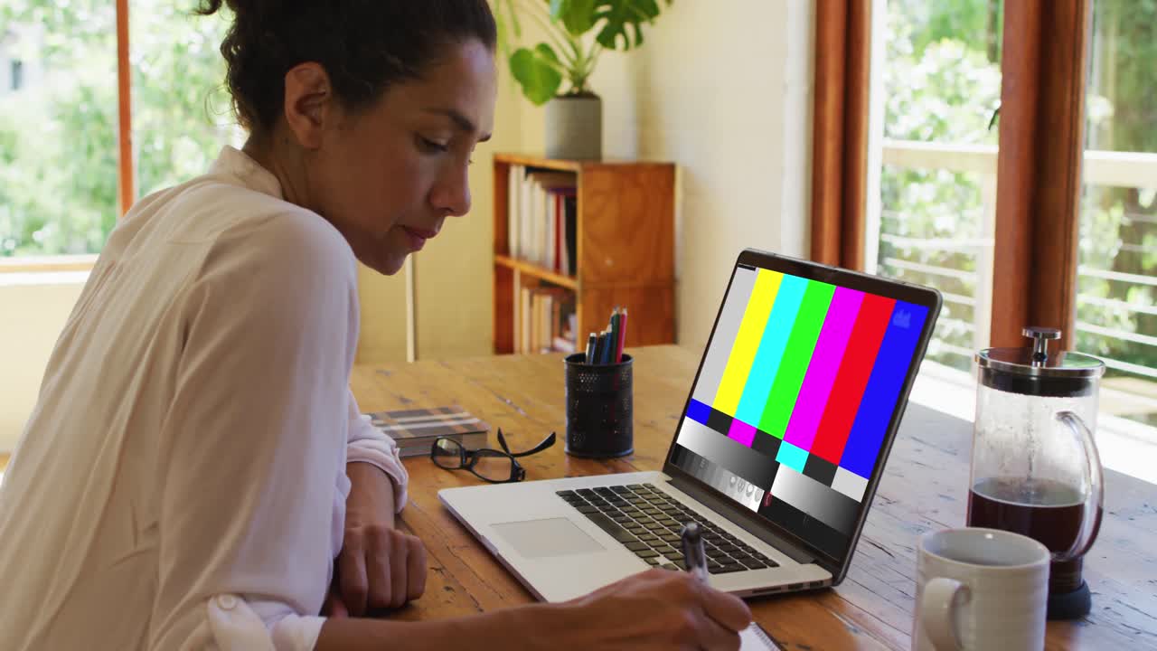 mujer de negocios de raza mixta sentada en un escritorio usando una computadora portátil haciendo una videollamada con interferencia