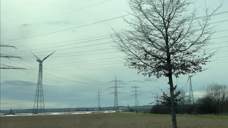 power line with many straw poles and wind turbines next to it in the evening sky
