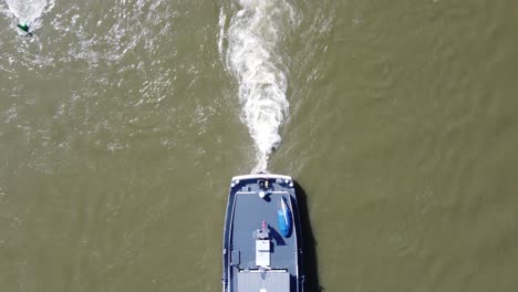 Popa-Del-Barco-Y-Estela-De-Propulsión-De-Barcaza-Navegando-Río-Arriba,-Aérea