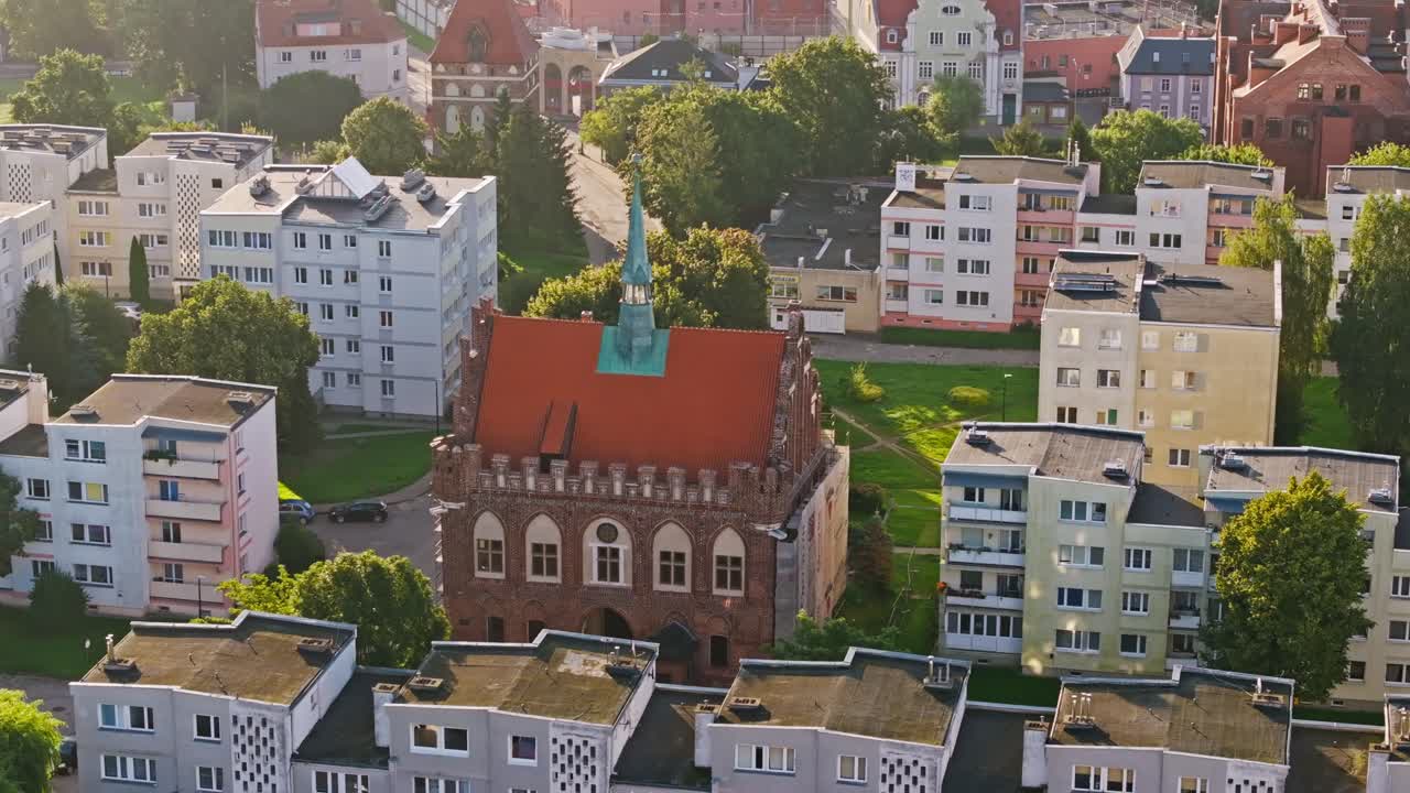 Golden morning light highlights Malbork Town Hall’s Gothic red brick facade