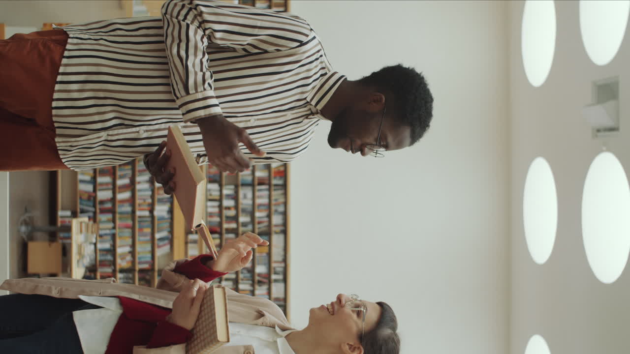 Afro Man and Caucasian Woman Discussing Books in Library