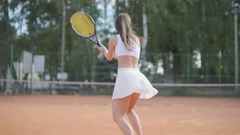 a young woman practicing tennis on an outdoor court with a coach. the coach provides guidance as the player works on her technique, perfecting her strokes in an athletic training session.