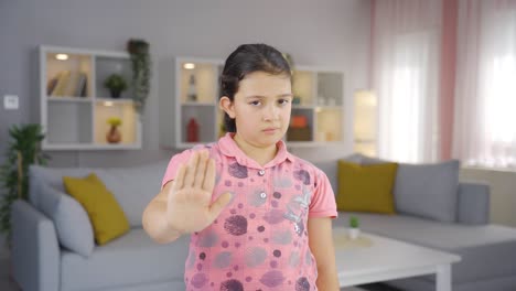 niña haciendo una señal de alto para la cámara.