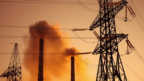 polluting factory at dawn. electric towers next to dirty smoke emitting from factory pipes at sunset. climate change. ecological disaster.