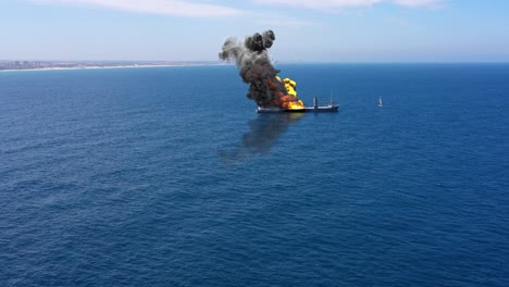 cargo ship burning on fire with large scale smoke-aerial