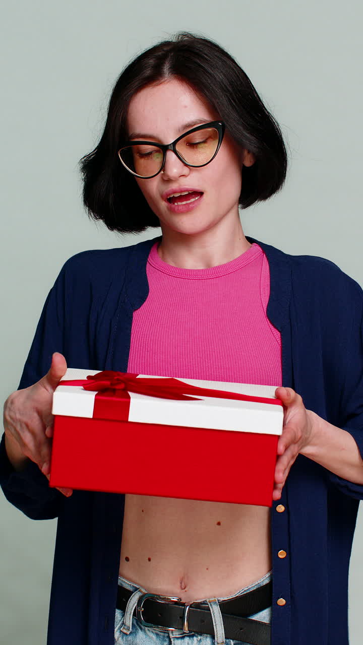Excited happy woman extending hands forward holding birthday gift box expressing surprise present