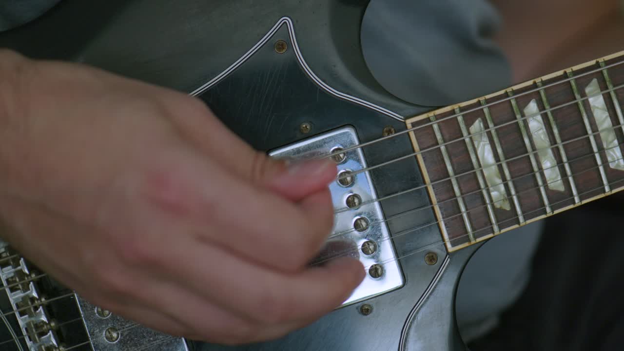 Man playing an electric guitar soloing with his right hand on camera