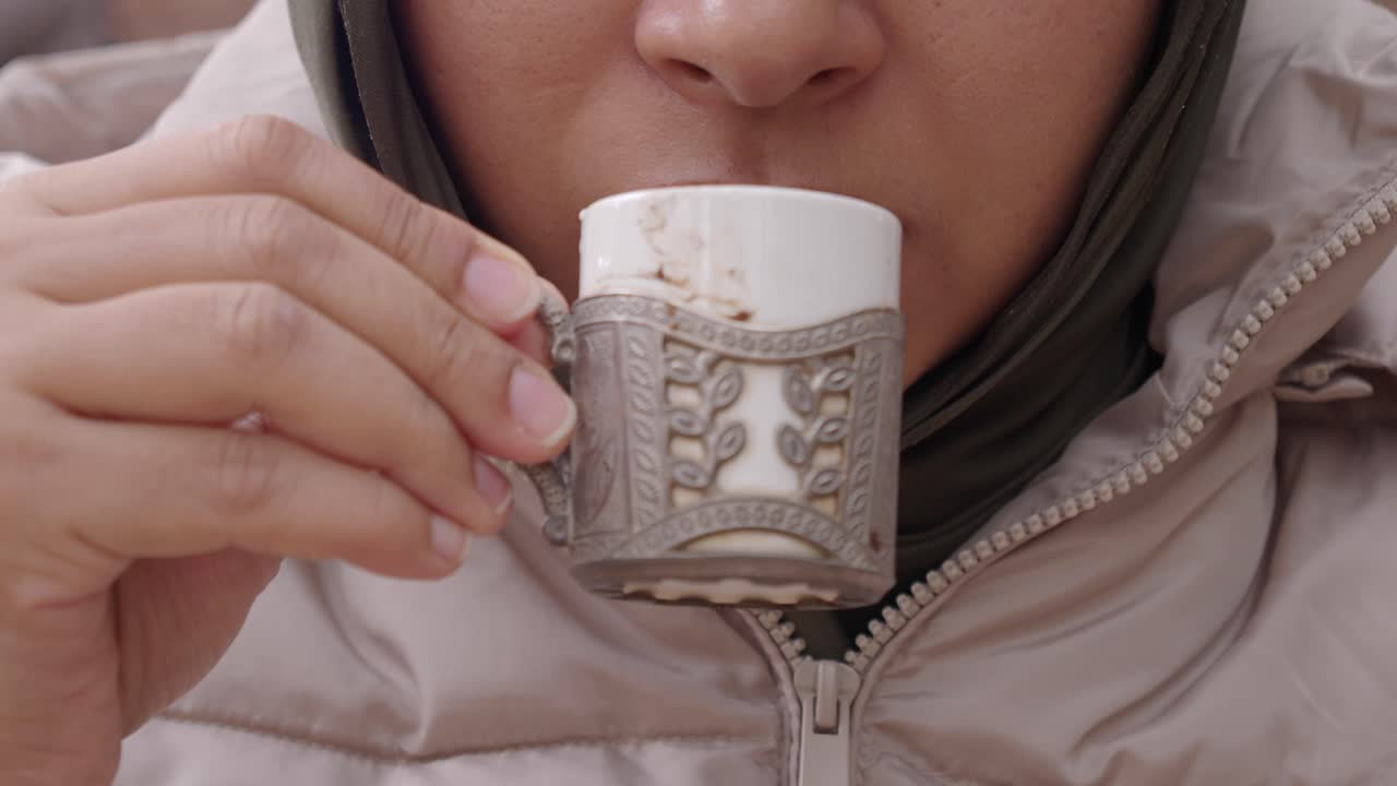 한 여성이 커피를 마시고 초콜릿을 먹습니다.