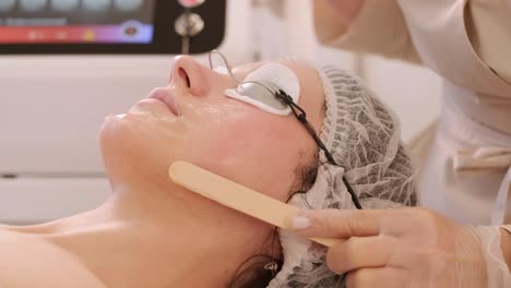 woman receiving radiofrequency lifting procedure around eyes for her face skin rejuvenation at aesthetic cosmetology center