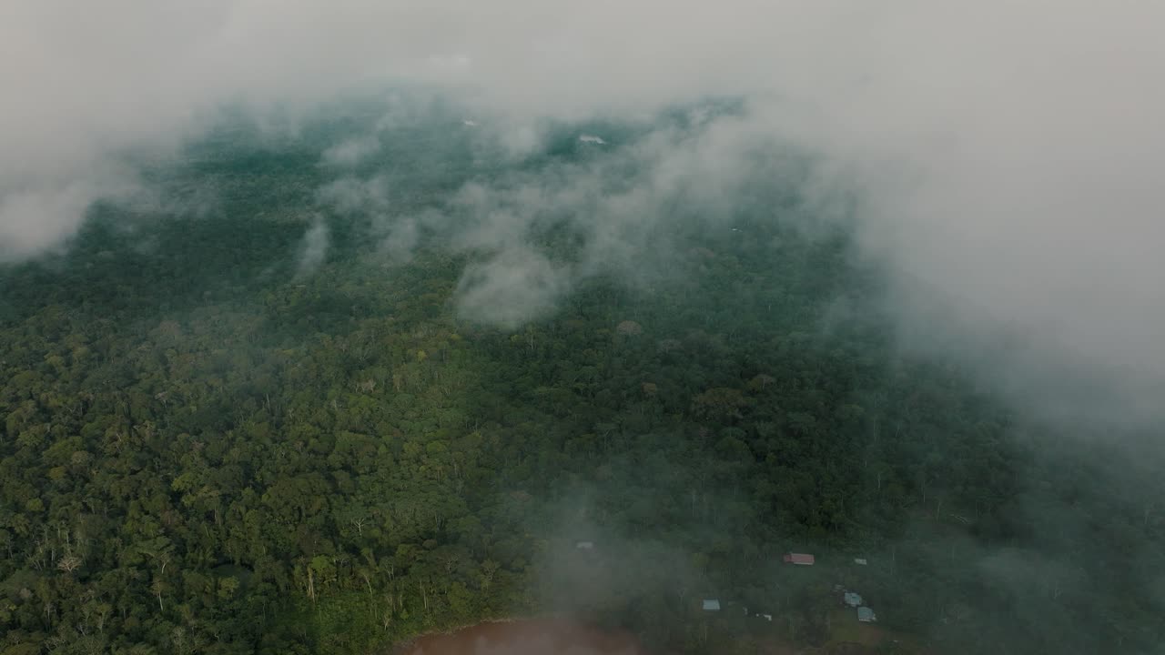 vuelo descendente a través de las nubes que muestran las copas de los árboles de la selva y el río amazonas en perú